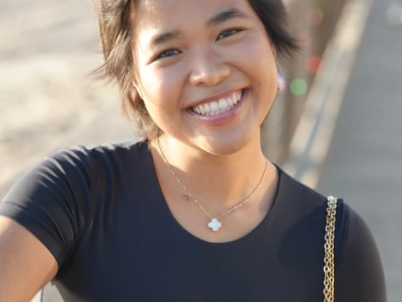 Person with black shirt and small purse smiling