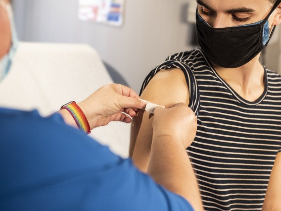 Nurse putting bandaid on student after vaccination