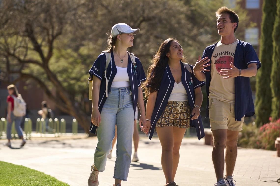 Group of three students walking around campus.